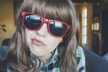 Funny portrait of a young woman wearing red sunglasses