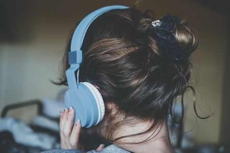 Young woman listening to music and wearing cozy clothes