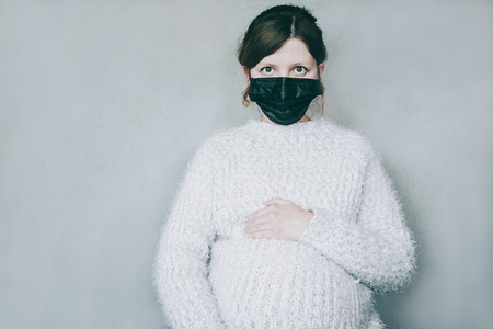 Young pregnant woman wearing a mask during covid 19 pandemic