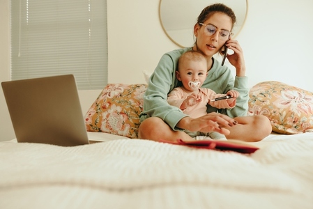 Working mom taking a phone call while sitting with her baby