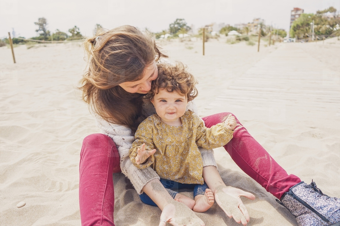 Young mom playing with her baby in the sand