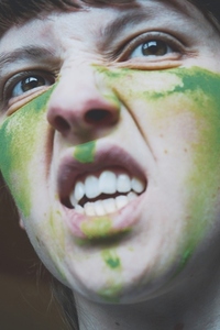 Angry young woman with her face painted with green dust