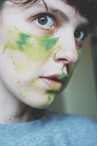 Moody portrait of a young woman with her face painted of green