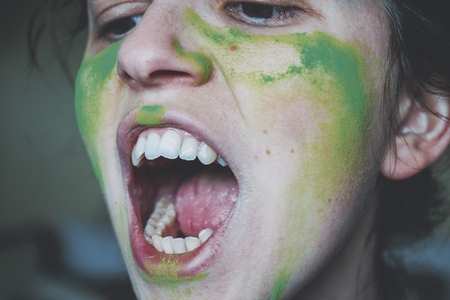 Angry young woman with her face painted with green dust