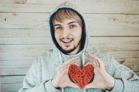 Young cool man holding a red heart