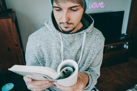 Young man reading a book in his home