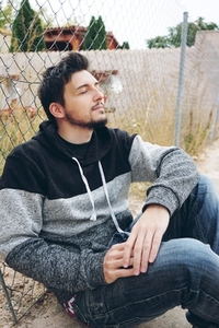 A young attractive man in calm sitting on ground and a outdoor f