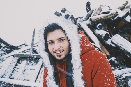 Young man enjoying a snowy day wearing a fur hat and a red hoodi