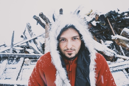 Young man enjoying a snowy day wearing a fur hat and a red hoodi