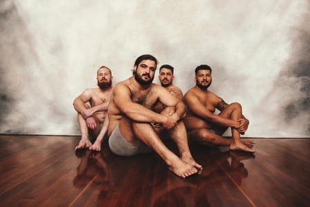 Shirtless men sitting on the floor in a studio