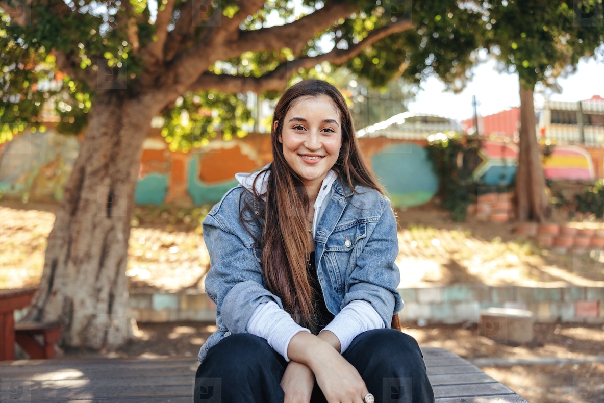 Cheerful teenage girl smiling at the camera in an urban park