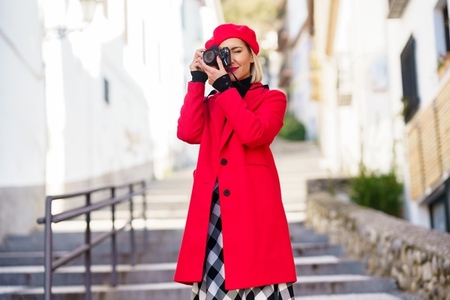 Woman taking a photograph with a reflex camera wearing red winter clothes