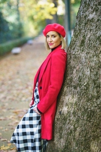 Beautiful middle aged woman leaning on a tree trunk in a charming urban park