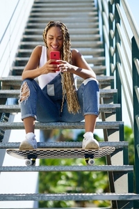 Black woman  with coloured braids  watching something funny on her smartphone