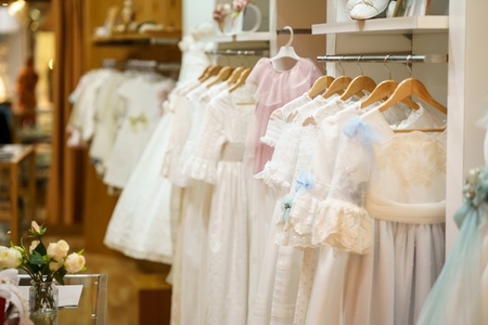 Display rack with first communion dresses for girls in a luxury childrens clothing shop