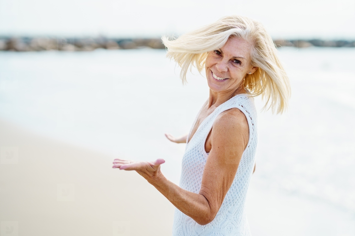 Happy mature woman walking on the beach  spending her leisure time  enjoying her free time