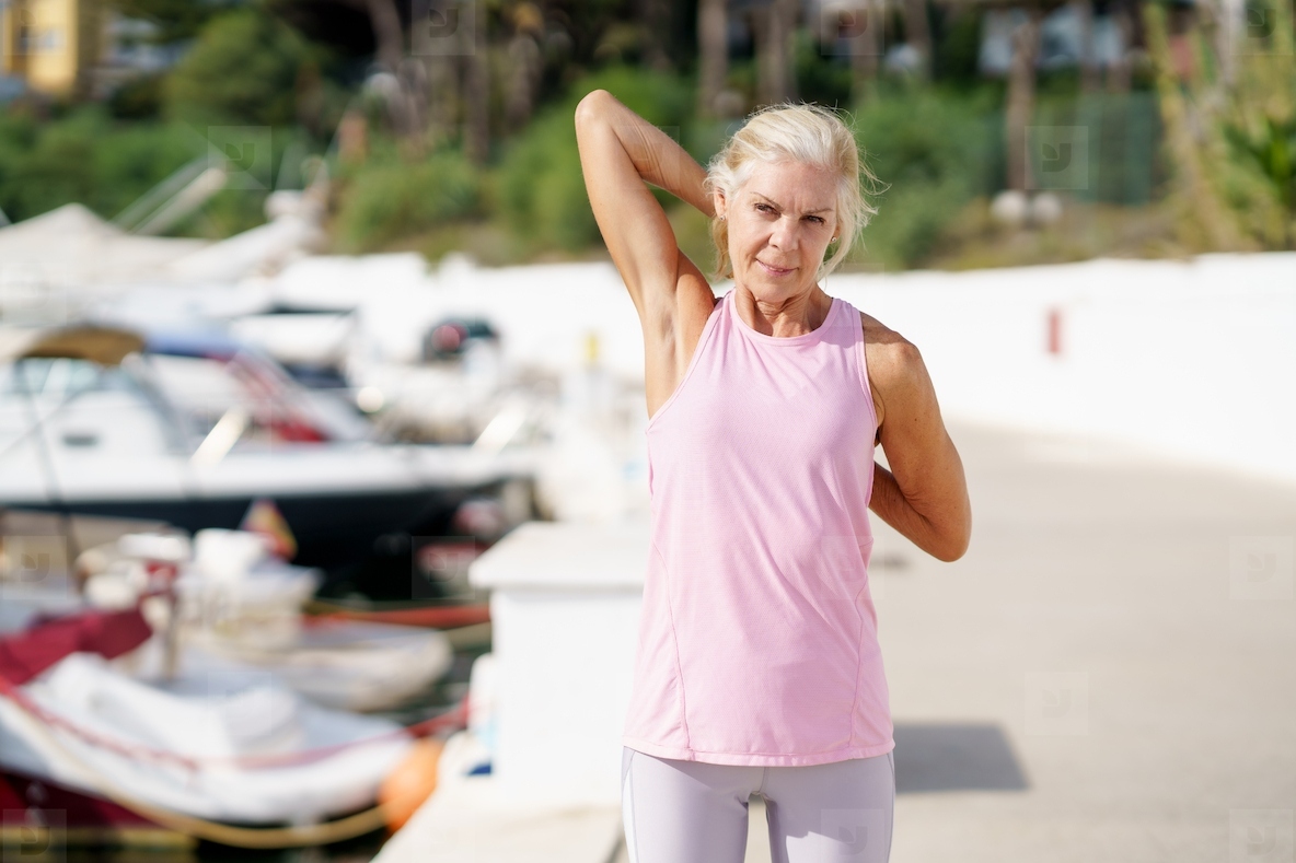 Senior woman in fitness clothing stretching her arms after exercise