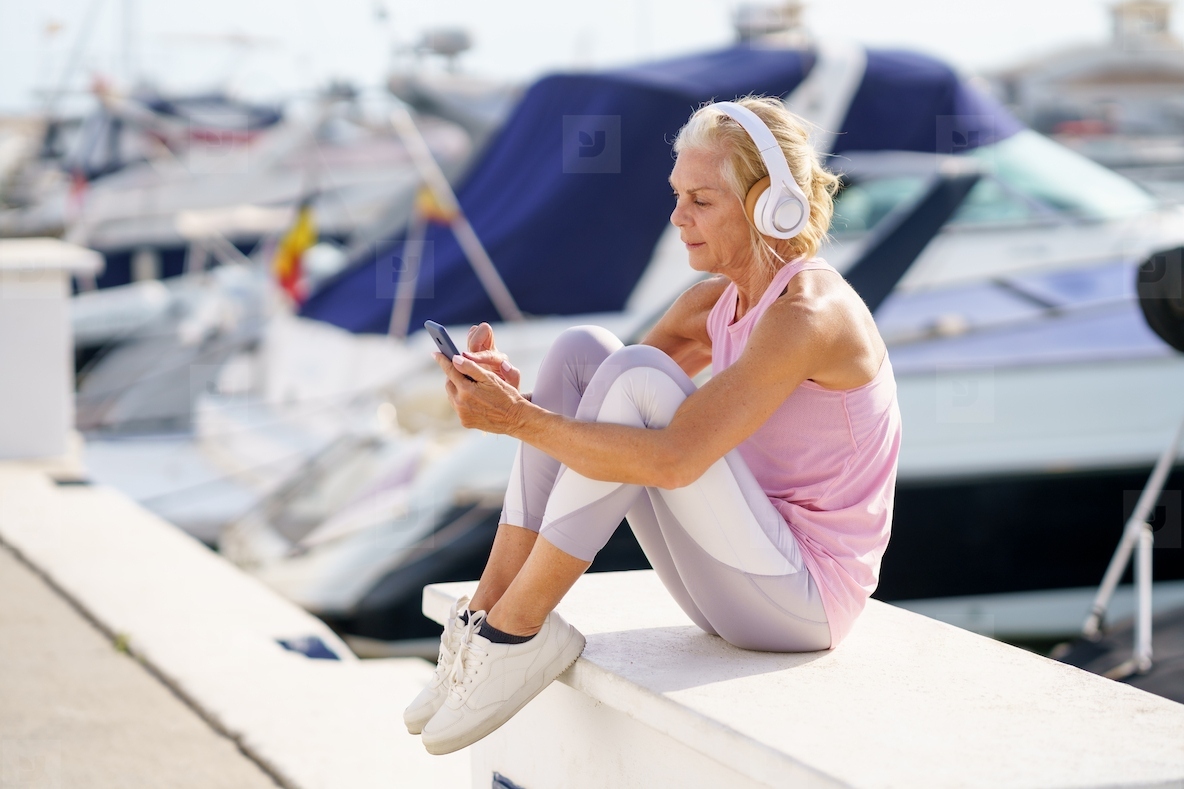 Mature sporty female taking a break to check a fitness app on her smartphone