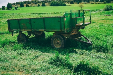 Green and old trailer abandoned in a green field