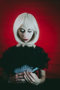 Vintage style portrait of a blonde woman covering by a hand fan