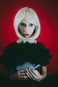 Vintage style portrait of a blonde woman covering by a hand fan