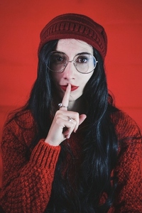 Young woman asking for silence against a red background