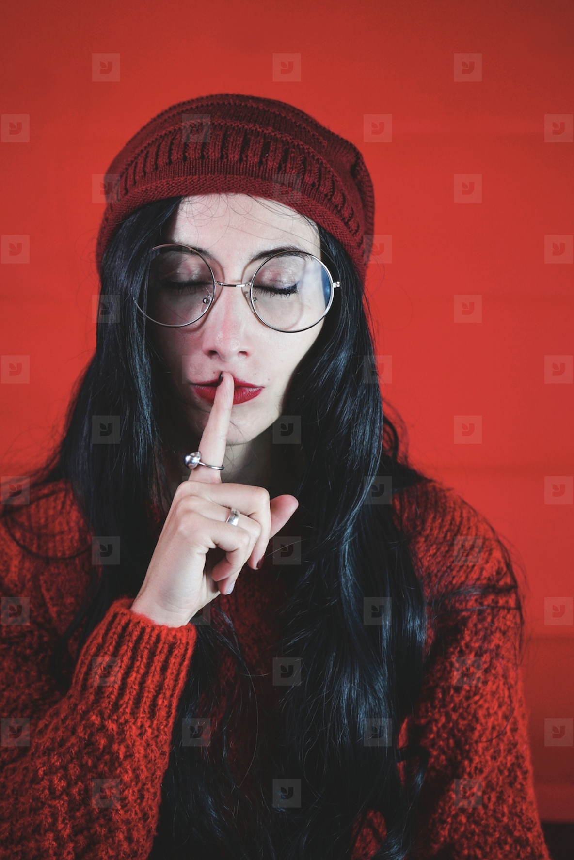 Young woman asking for silence against a red background