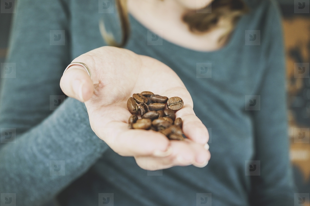 Woman hand holding natural coffee grains