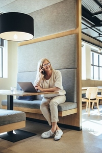 Mature businesswoman taking a phone call in a modern workspace