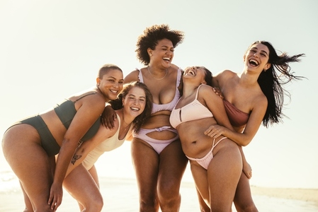 Hilarious female friends laughing at the beach