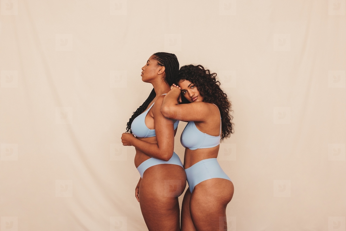 Two female friends standing in blue underwear in a studio