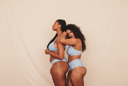 Two female friends standing in blue underwear in a studio