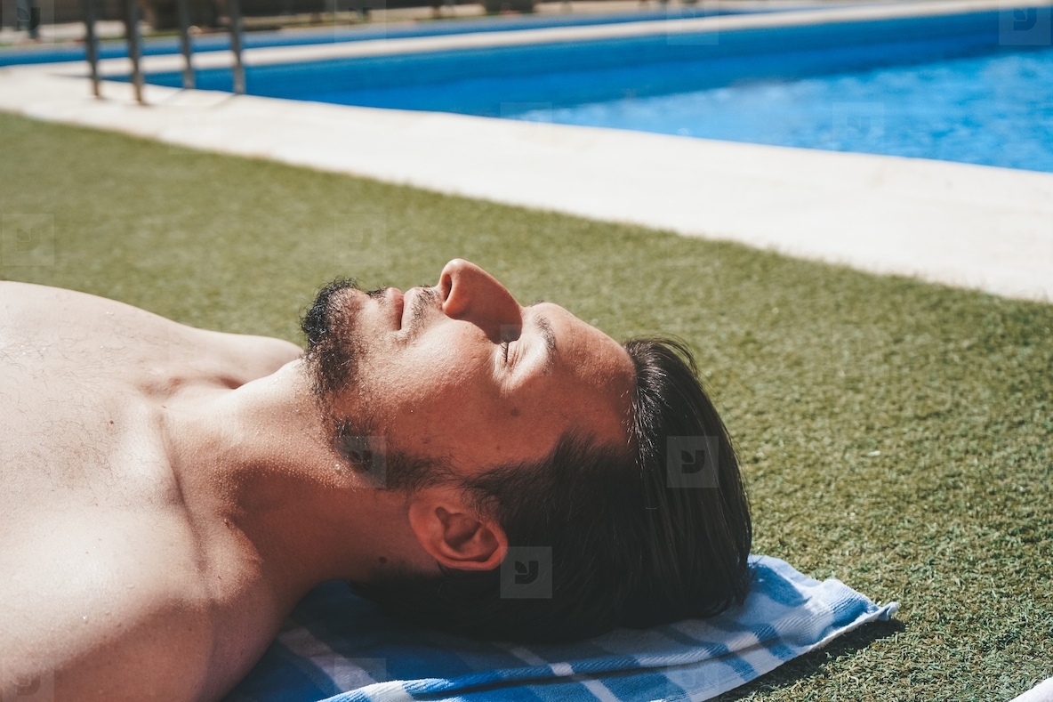 YOung man enjoying a sunbath at the swimming pool
