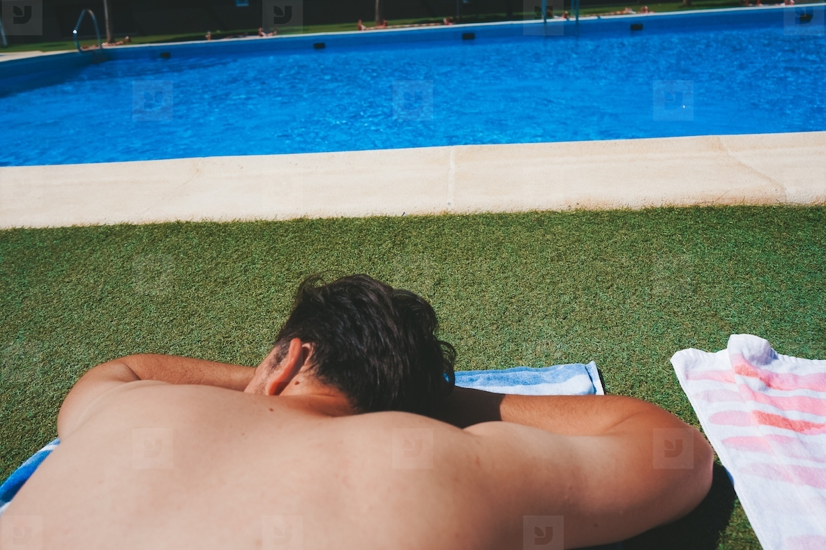 YOung man enjoying a sunbath at the swimming pool