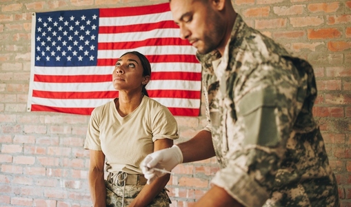 Male nurse preparing to vaccinate a servicewoman in the army clinic