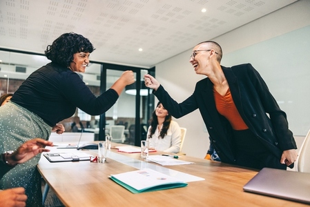 Cheery businesswomen fist bumping each other before a meeting