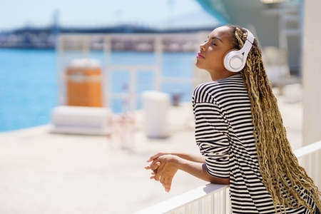 Young black woman listening to music while enjoying the view of the seaport