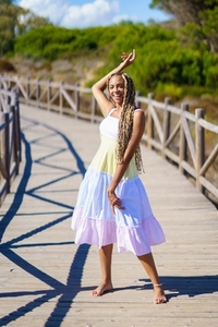 African female wearing a beautiful dress on a boardwalk on the beach