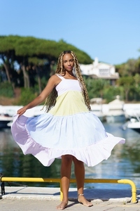 Black woman walking along a seaport wearing a nice summer dress
