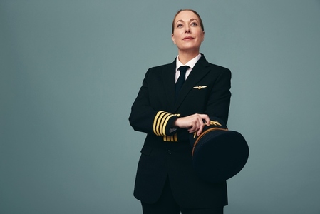 Female airline pilot looking away thoughtfully in a studio