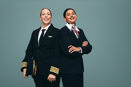 Happy pilot and flight attendant smiling at the camera in a stud