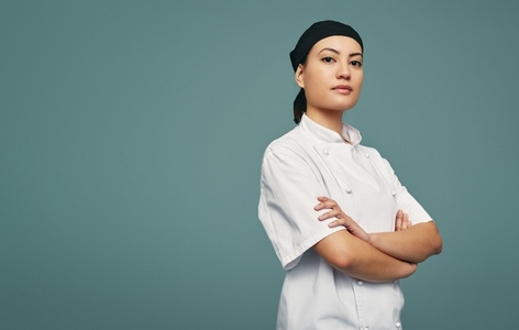 Professional chef standing with her arms crossed in a studio