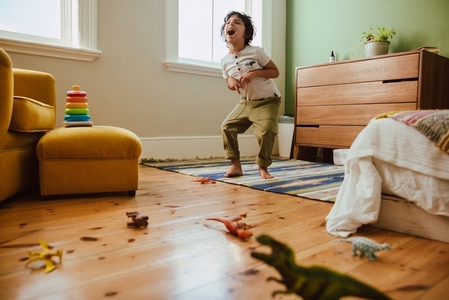 Creative young boy mimicking a t rex dinosaur in his play area