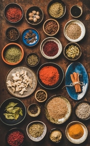 Flat lay of various spices in bowls over rusty background