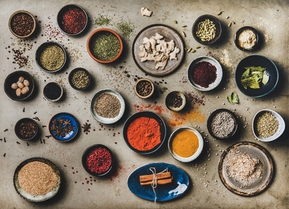 Flat lay of different spices in bowls over grey concrete background