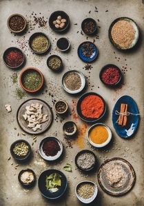 Flat lay of colorful spices in bowls over grey concrete background