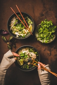 Vietnamese soup Pho Ga and womans hands with wooden chopsticks