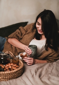 Young smiling brunette woman having breakfast in bed