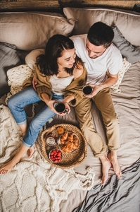 Young happy couple having breakfast in bed and hugging