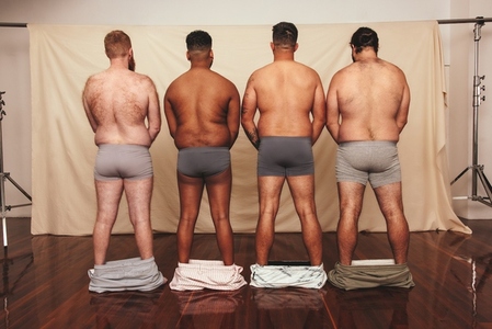 Unrecognizable men standing with their shorts dropped down